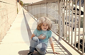 Paused for breath. Boy relax hunkering down on promenade. Boy child take short rest