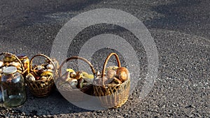 Paved country road in the mountains and three baskets of large porcini mushrooms for sale.