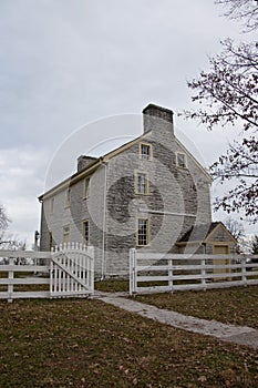 Paved pathway and open gate leads to old style Shaker home.