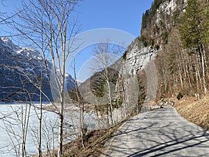 Paved road by the alpine resevoir lake KlÃ¶ntalersee Kloentalersee or Klontaler lake and in the KlÃ¶ntal alpine valley / Kloental