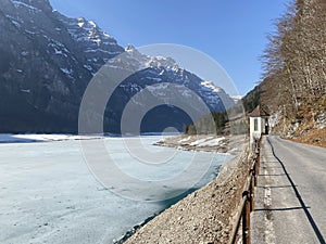 Paved road by the alpine resevoir lake KlÃ¶ntalersee Kloentalersee or Klontaler lake and in the KlÃ¶ntal alpine valley / Kloental