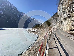 Paved road by the alpine resevoir lake KlÃ¶ntalersee Kloentalersee or Klontaler lake and in the KlÃ¶ntal alpine valley / Kloental