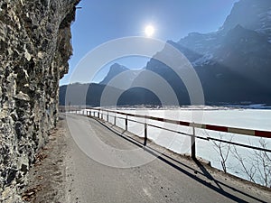 Paved road by the alpine resevoir lake KlÃ¶ntalersee Kloentalersee or Klontaler lake and in the KlÃ¶ntal alpine valley / Kloental