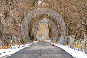 Paved road with chain link and barbed wire fence amid a snow covered terrain