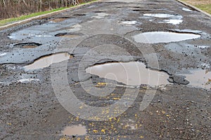 A paved road filled with many large potholes