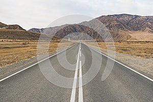 Paved road leading to mountains. Beautiful mountain landscape on the background.