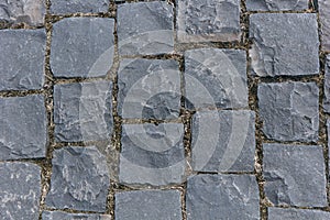 Paved with square granite pavement of dark gray color. The pavement laid with square stone cobbles of granite.