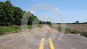 Pavement ends where it meets dirt road next to rural farmland