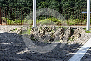 A pavement made of cobblestones in the center, protruding slate rocks and two flagpoles.