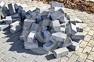 Pavement repairs and paving slabs laying on the prepared surface, with tile cubes in the background. Laying paving slabs in the