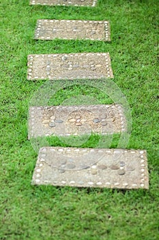 Pavement stone design in rectangle frame with flower shape patterns on green grass outdoor garden background