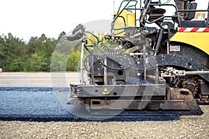 Pavement truck laying fresh asphalt on construction site, asphalting