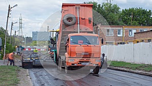 A paver finisher, asphalt finisher or paving machine placing a layer of asphalt during a repaving construction project photo