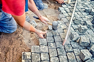 paving with granite stones, workers using industrial cobblestones for paving terrace, road or sidewalk