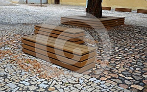 Paving gray brown beige color of natural stone boulders of irregular shapes and colors. Benches around a square and rectangular