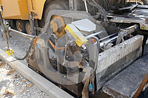 A paving machine placing fresh asphalt or bitumen on a gravel base during