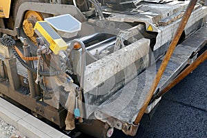 A paving machine placing fresh asphalt or bitumen on a gravel base during