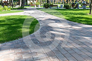 Paving with paving slabs. Landscape architecture of a park. Decorative garden winding pathway walkway and a green lawn