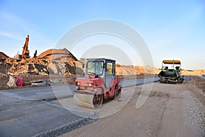 Paving roller machine during road work. Road roller at construction site for paving works. Screeding the sand for road concreting