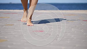 On the paving slabs, against the background of the sea, women`s legs are dancing, barefoot. summer hot day