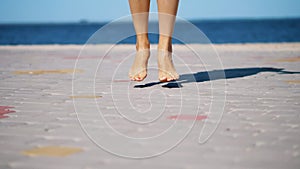 on the paving slabs, against the background of the sea, women& x27;s legs are dancing, barefoot. summer hot day