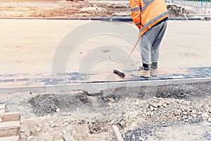 Paving stone workers filling joints of the block paved footpath with dry sand during the construction of new road