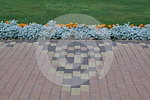 Paving stones laid out in a pattern along the flowerbed with flowers and green grass