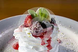 Pavlov dessert with whipped whites and berries on a white plate