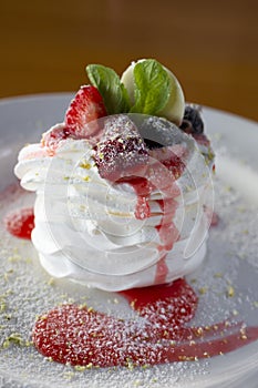 Pavlov dessert with whipped whites and berries on a white plate