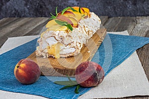 pavlova as roulade variant with peach cream, peaches, whipped cream and mint leaves