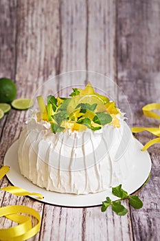 Pavlova cake with cream and fresh fruits - lime, carambola and green mint leaves. Close up of Pavlova dessert with yellow and