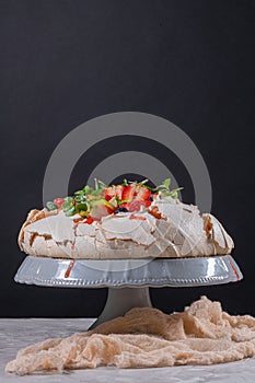 Pavlova cake with cream and fresh summer berries and kiwi on wooden background. Close up of Pavlova dessert with forest fruit and