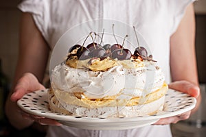 Pavlova cake with fresh cherry in the woman hands horizonta