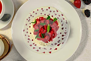 Pavlova dessert with cream mint and strawberry in a white plate on a white table