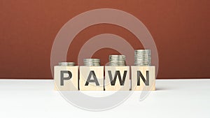 pawn text on wooden blocks with coins on brown background