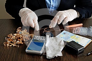 Pawnshop worker verify golden jewelry on many golden and silver jewelleries, scales and money background. Customers Buy and Sell