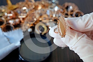 Pawnshop worker verify jewellery on many golden and silver jewelleries and money background. Customers Buy and Sell Precious