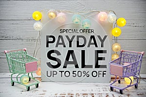 Pay Day Sale text message and shopping trolley cart on wooden background