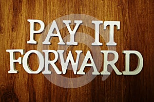 Pay It Forward alphabet letter on wooden background