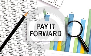 PAY IT FORWARD text on white card on the chart background