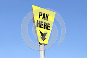 Pay here sign for car parking against blue sky
