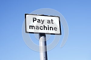 Pay at machine sign against empty blue sky