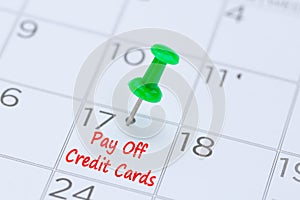 Pay Off Credit Cards written on a calendar with a green push pin