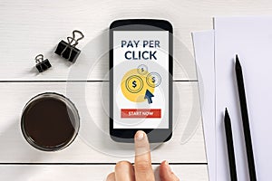 Pay Per Click concept on smart phone screen with office objects photo