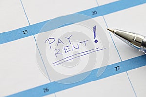 Pay rent is written on sheet of calendar with ballpoint pen closeup