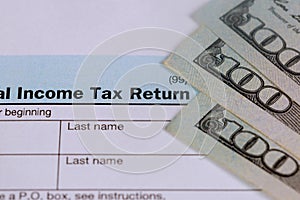 Pay tax concept USA Tax Form 1040 with 100 US dollar bills