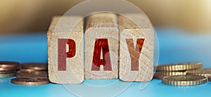 Pay word on Wooden blocks with coins around. Selective focus. Payments Fees and Taxes concept