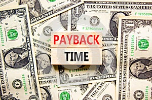 Payback time symbol. Concept words Payback time on wooden blocks. Beautiful background from dollar bills. Business and payback