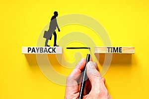 Payback time symbol. Concept words Payback time on wooden blocks. Beautiful yellow table yellow background. Businessman hand.