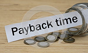 PAYBACK TIME words on a white strip of paper with a can of money photo